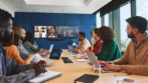 Team collaborating in a modern conference room using video conferencing technology for a hybrid meeting, showcasing a large display screen with remote participants